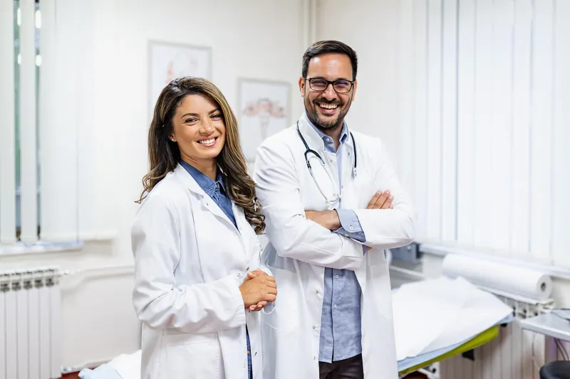 Médica e médico do trabalho sorrindo em consultório